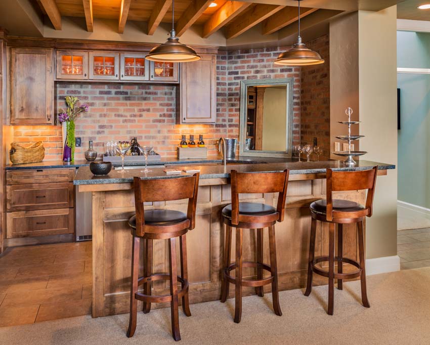 Beautiful kitchen bar with brick wet backsplash, high chairs, and pendant lights