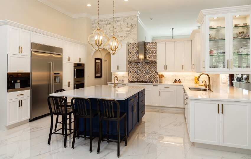 Beautiful kitchen with blue island, patterned backsplash, pendant lights, and marble floor