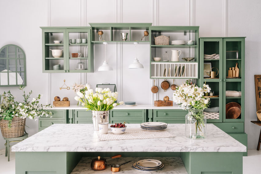 Beautiful kitchen with quartzite countertop, center island, green shelves, and white wall