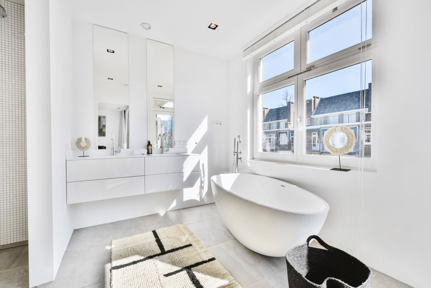 Bright and beautiful bathroom with acrylic tub, windows, mirror, and ceiling lights