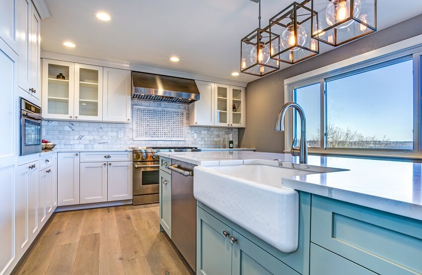 Bright kitchen with green island, farm sink and brick backsplash