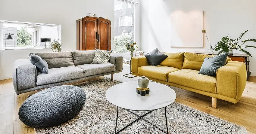 Bright living room with yellow and grey sofa, pouf chair, and coffee table