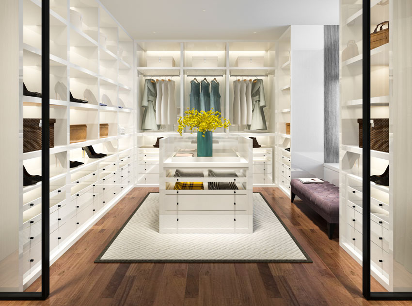 Bright walk in closet with center island, cabinet lighting, and wood floor