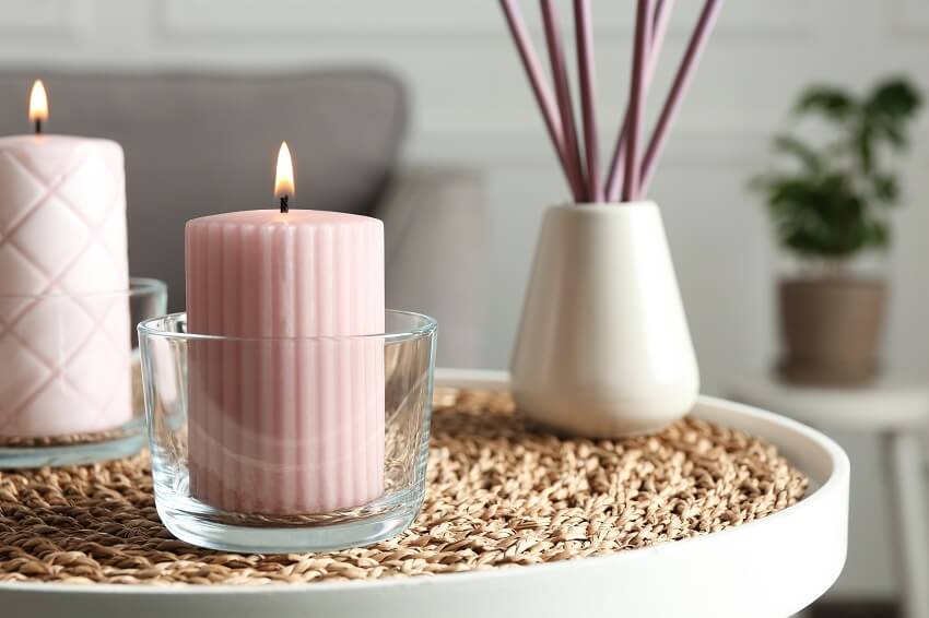 Burning scented candles and air reed freshener on round table