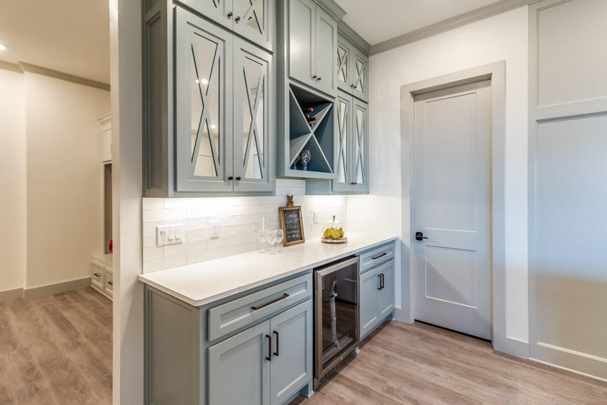 Butlers pantry with wet bar backsplash, cabinets, and wood flooring