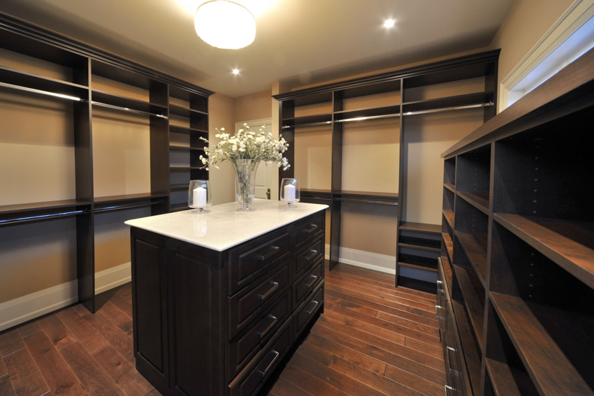 Closet with semi flush mount ceiling lights, center island, countertop, and wood flooring