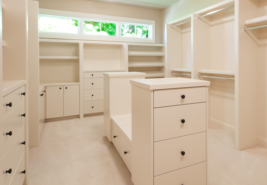 Closet with white cabinets and customized seat in the center