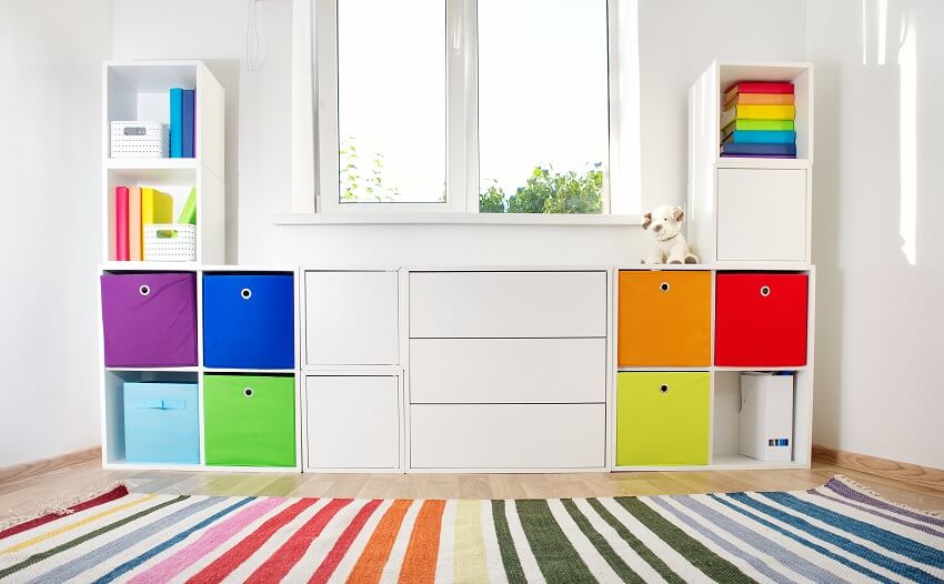 Colorful playroom with white walls storage cabinet cubby holes rainbow carpet and a window