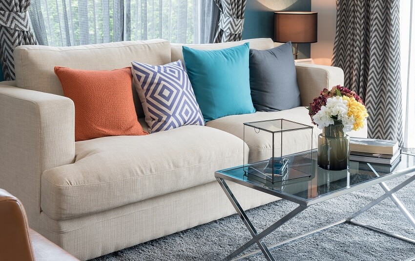 Colorful throw pillows on modern sofa and a glass coffee table in modern living room