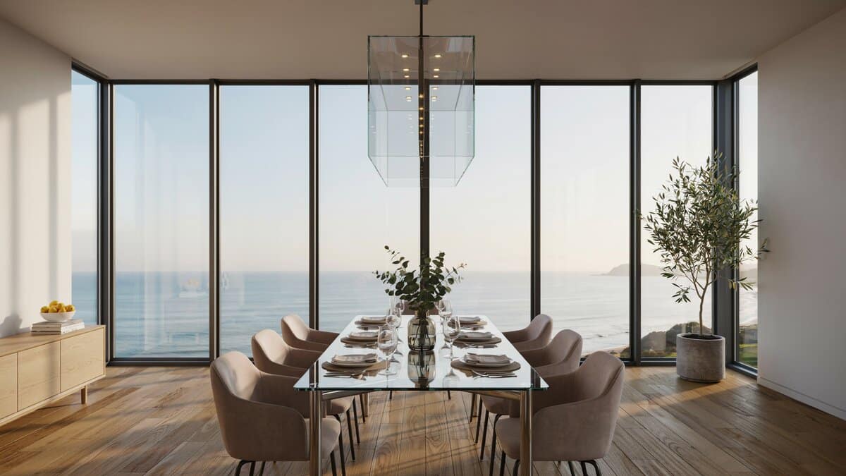 Glass dining table facing floor to ceiling windows overlooking a calm blue ocean
