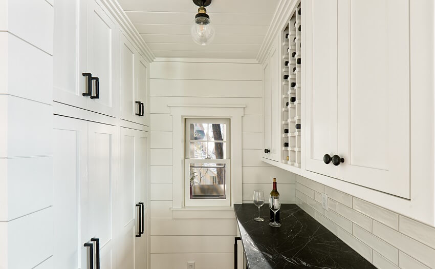 Contemporary hidden butlers pantry featuring wine storage cabinet, black quartz countertop, and pantry storage
