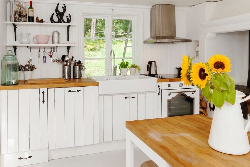 Country style kitchen with beadboard backsplash and cabinet, and a vase of sunflower on an island