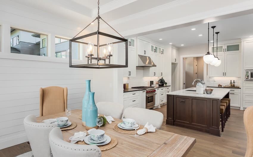 Dining and kitchen area with wood floors, pendant lights, island, and white beadboard walls