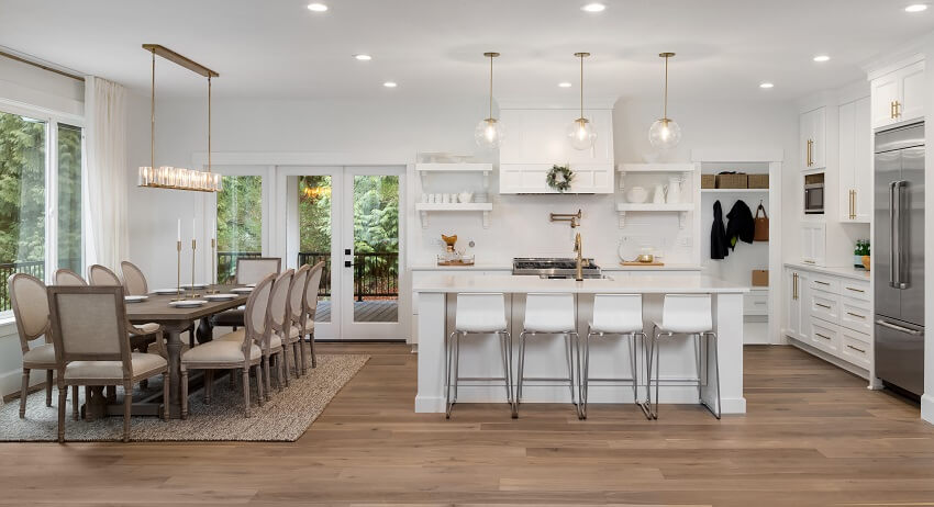 Dining room and kitchen with pendant lights, wood floor, white island and cabinets