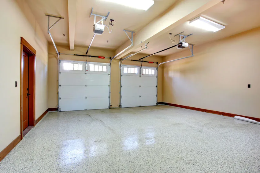 Empty garage with sealed epoxy floor, door opener, and ceiling lights