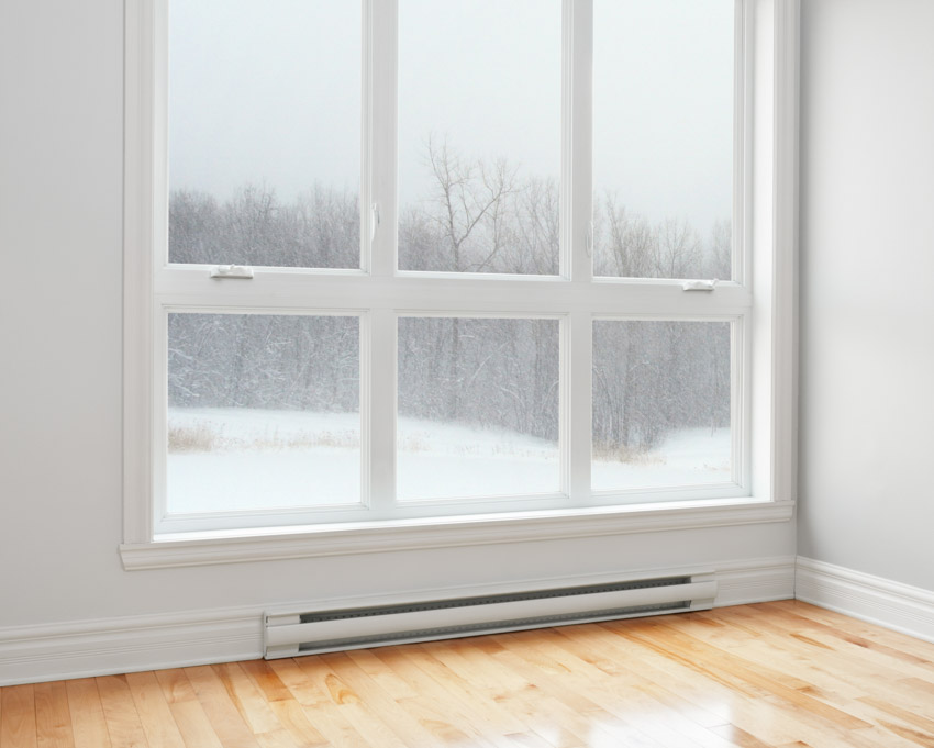 Empty room with electric baseboard heater, wood floor, white wall, and windows