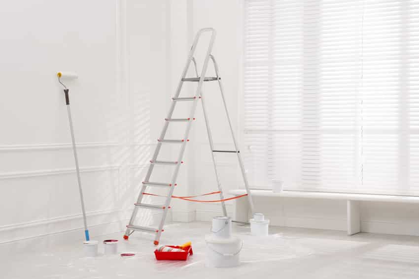 Empty room with ladder, white walls, and window
