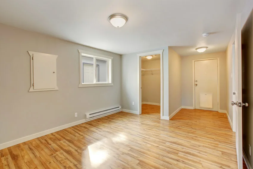 Empty room with wooden flooring, electric baseboard heater, and ceiling lights