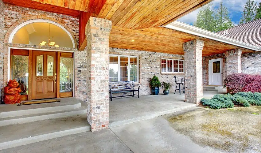 Brick house with stained glass wooden door and patio with brick columns