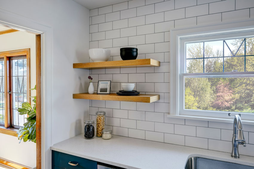 Floating shelves on tiled kitchen wall with countertops, and windows