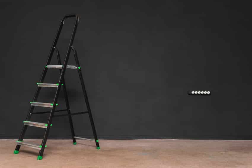Folding step ladder near black wall
