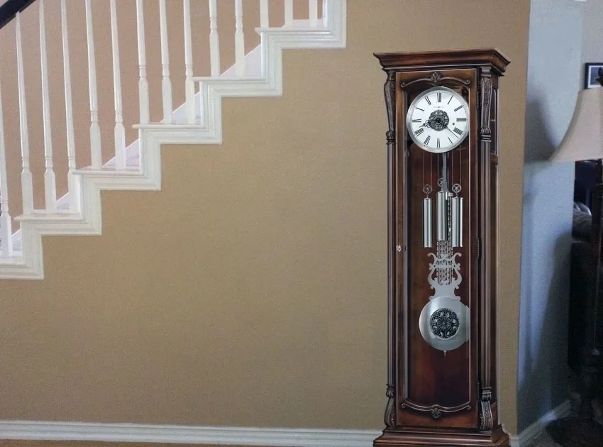 Grandfather-style clock near painted staircase