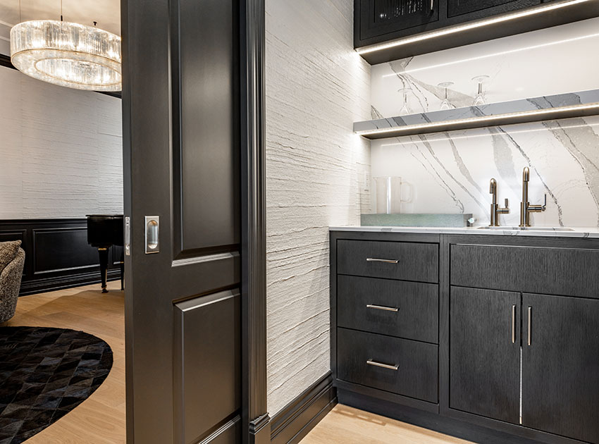 Hallway bar with white quartz backsplash, dark cabinets and sliding pocket door