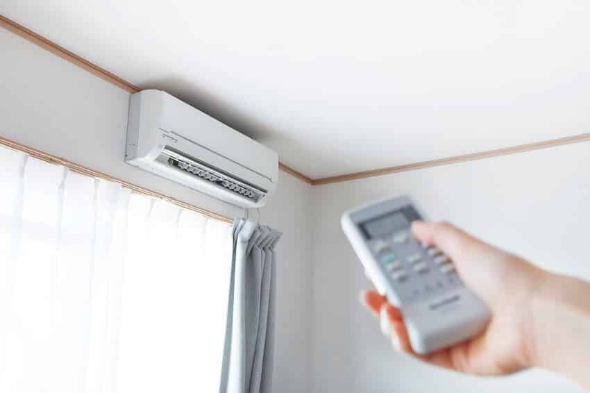 Hand with remote control directed on the split ductless heat pump