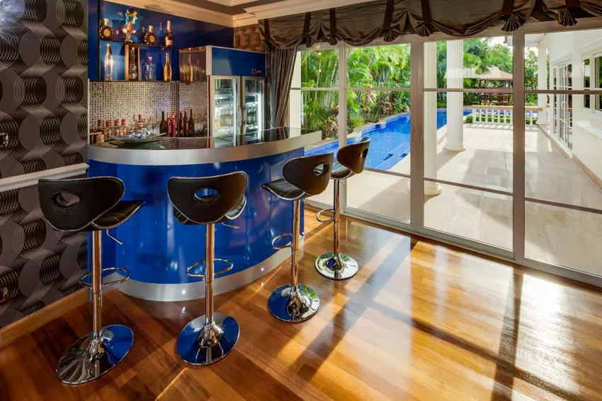Home bar with wet backsplash, high chairs, glass door, and wood floors