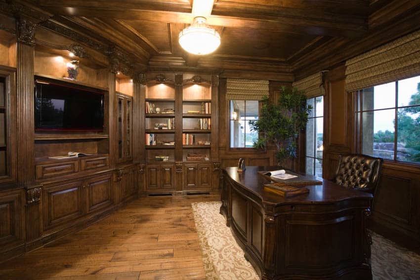 Home office with executive desk, ceiling light, dark wood cabinets, and windows