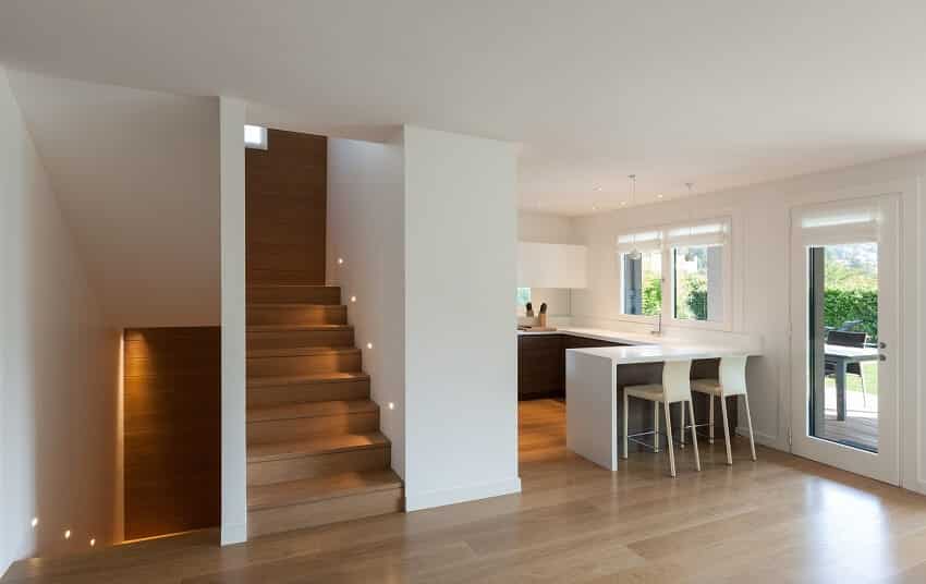 House interior with white walls, kitchen, and stairs with vinyl plank flooring