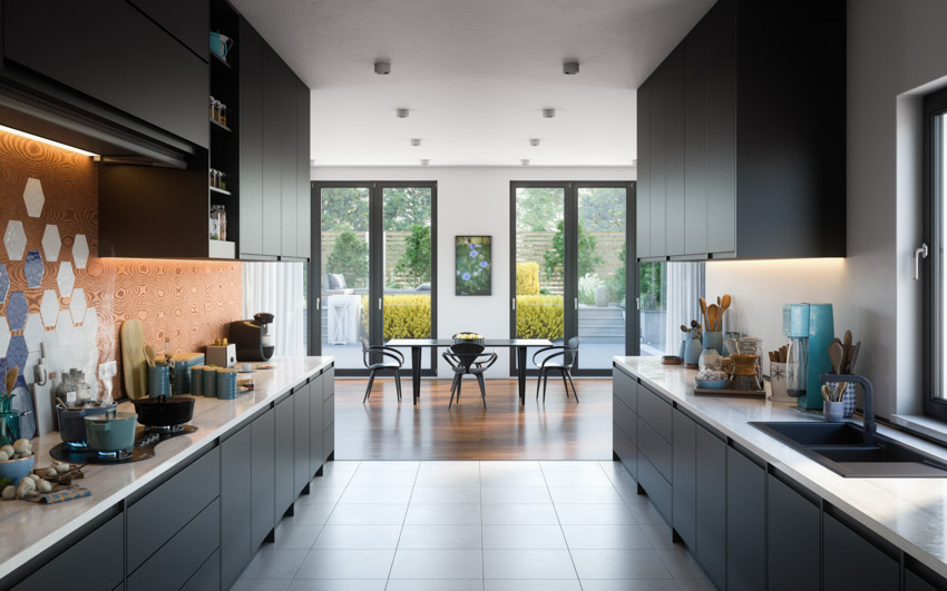 Kitchen with tile wall, black cabinets, and white solid surface counters