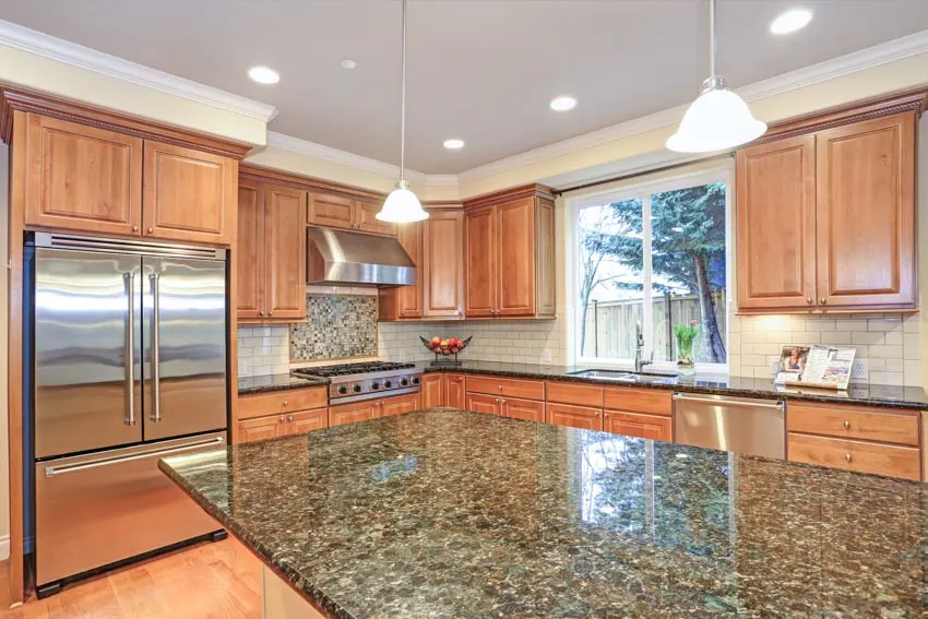 Kitchen with agate countertop, center island, wood cabinets, hanging light, and window