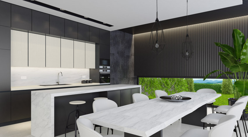 Kitchen with black accent wall, island, table, chairs, and hanging lights