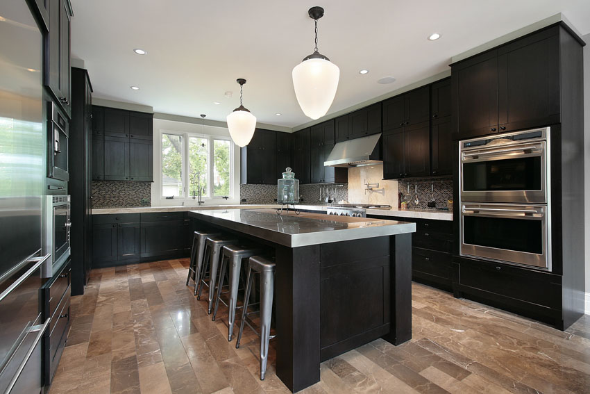 Kitchen with black cabinets, center island, metal countertop, wood floor, and pendant lights