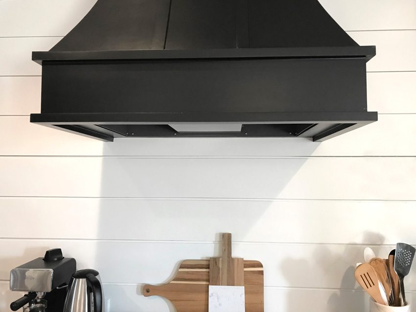 Black range hood and wood shiplap wall