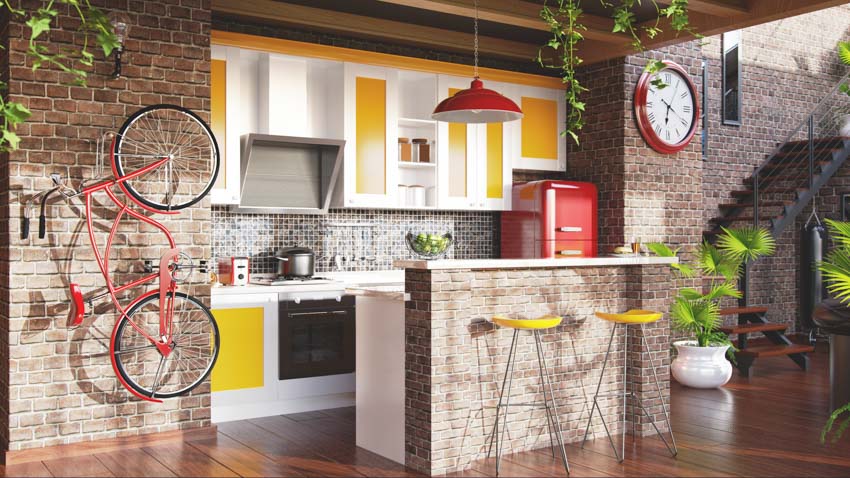 Kitchen with brick accent wall, countertop, yellow cabinets, hanging light, and wood flooring