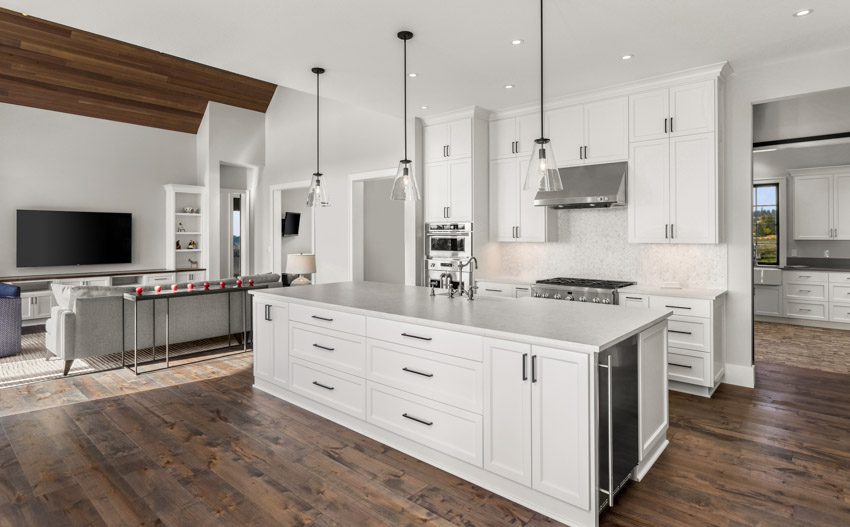 Kitchen with center island, glassos countertop, hanging lights, white cabinets, drawers, and wood floor