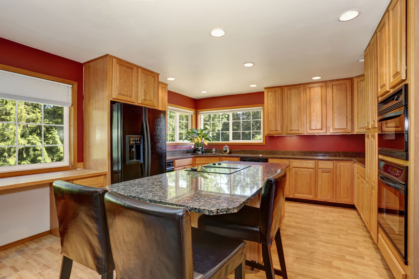 Kitchen with red painted walls, agate surfaces, solid cabinets, recessed lights, and windows