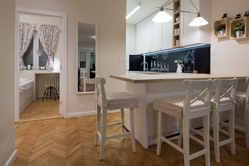 Kitchen with chalkboard backsplash, herringbone floor, and chairs