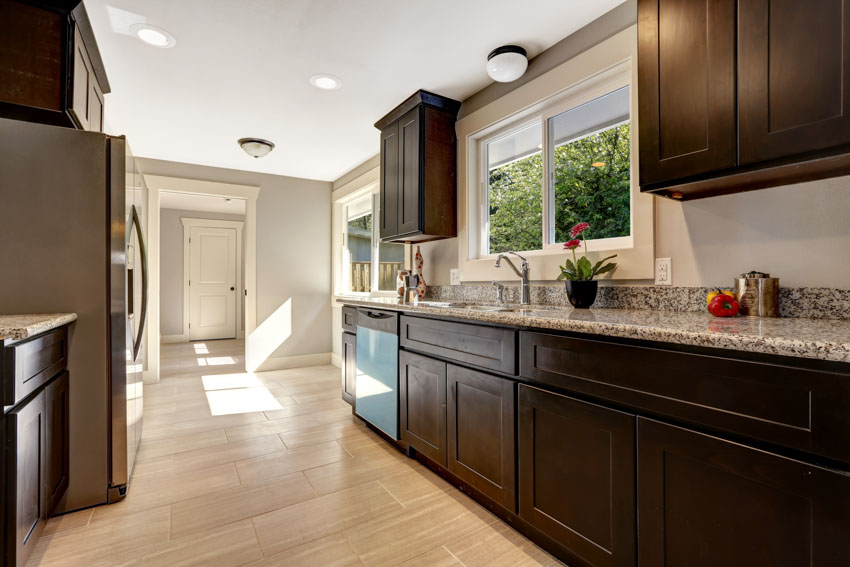 Kitchen with dark cabinets, light wood flooring, windows, and countertop