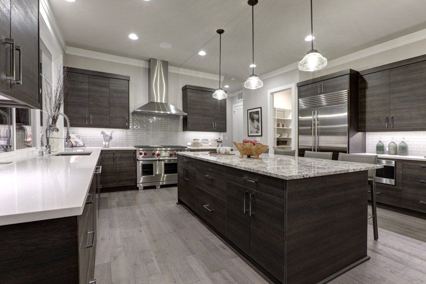 Kitchen with dark cabinets, wood flooring, countertops, pendant lighting, fixtures, and range hood