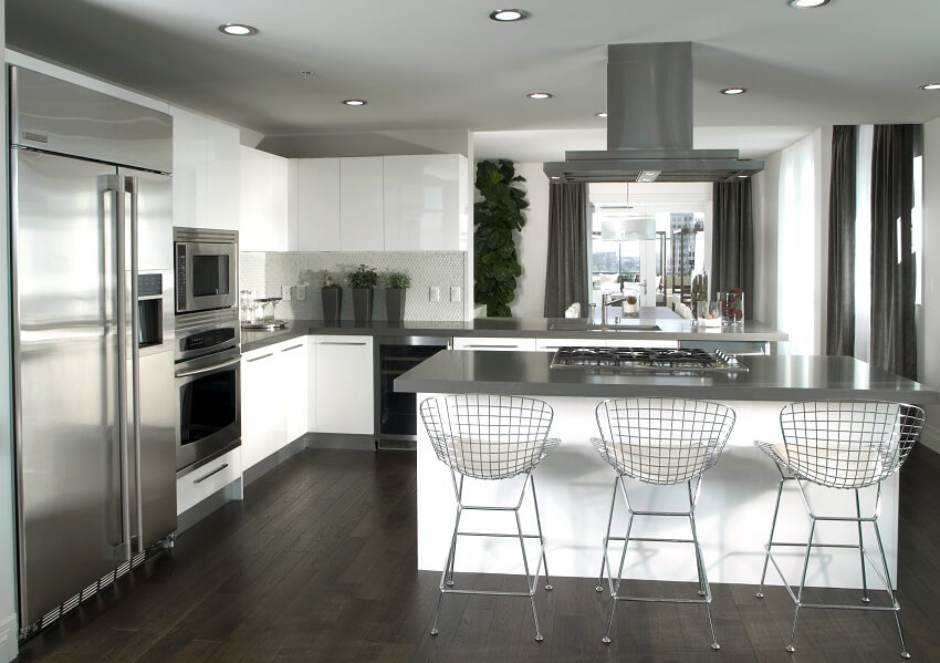 Kitchen with dark wood floor, white cabinets, and island with gray countertop, barstools, and cooktop