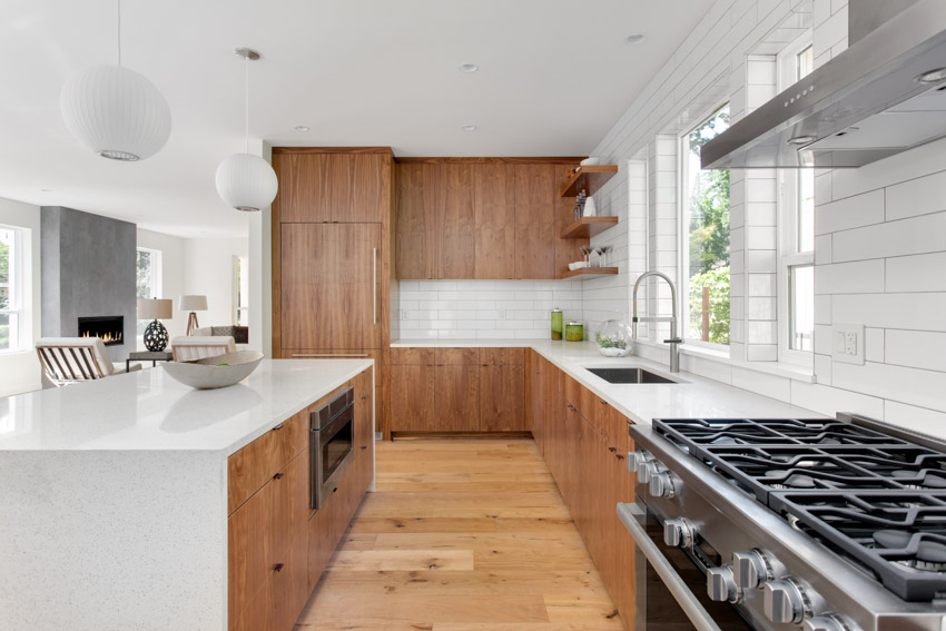 Kitchen with floating wood cabinets, center island, tile backsplash, and windows