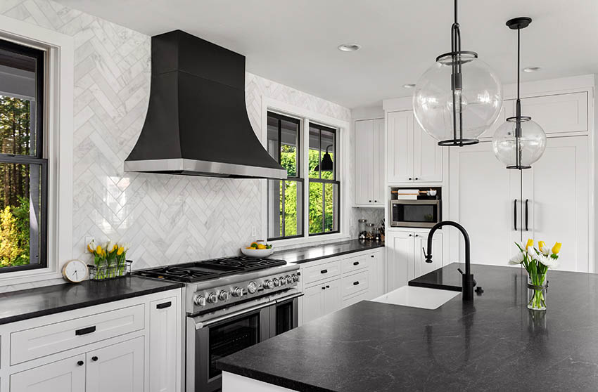 Kitchen with full wall backsplash tile in herringbone design soapstone countertops white shaker cabinets
