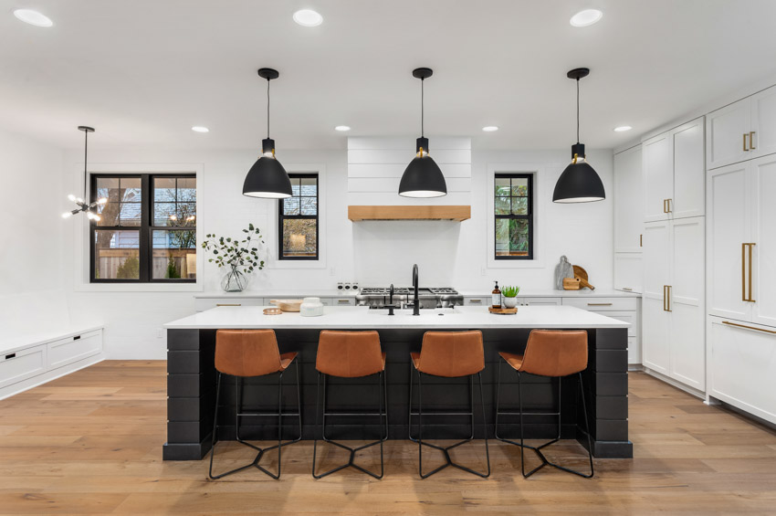 Kitchen with glassos countertop on center island, high chairs, pendant lights, wood floor, and windows