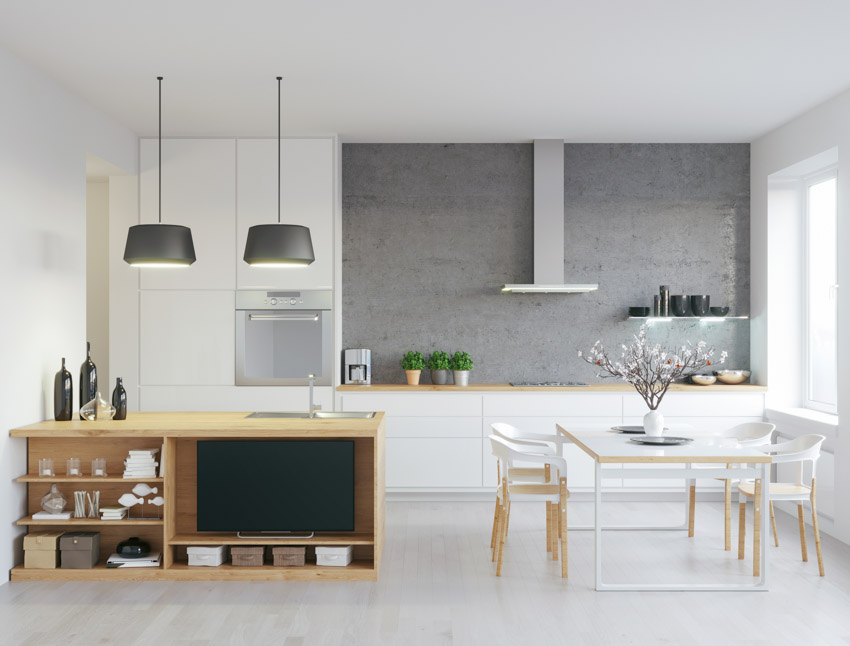 Kitchen with gray accent wall, range hood, table, chairs, cabinets, and windows