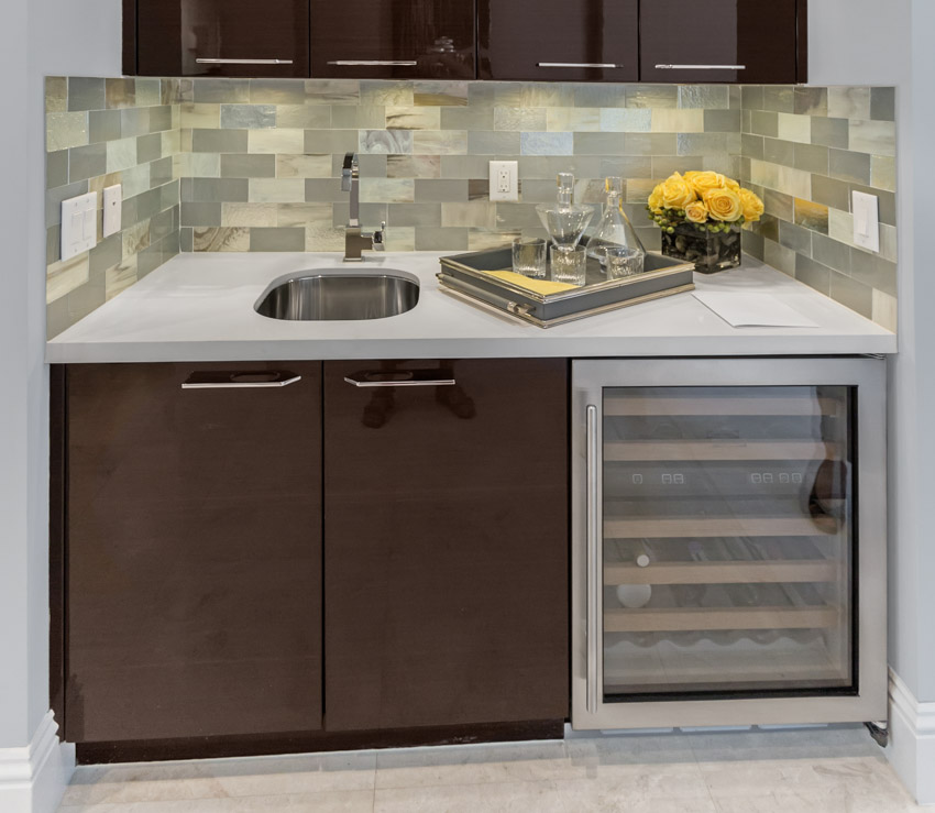 Kitchen with home bar, wine cooler, backsplash, cabinet, countertop, sink, and faucet