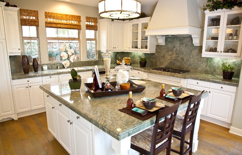 Kitchen with marble countertops and backsplash, bamboo shades on windows, and large island