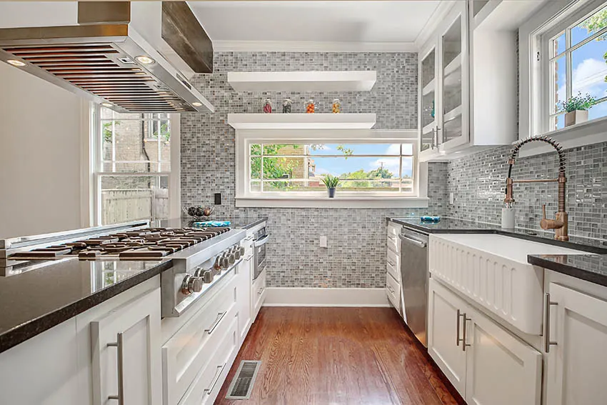 Kitchen with mosaic tile backsplash to ceiling, white cabinets, farmhouse sink and black granite countertops